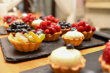 coloured cupcakes with fruits, cream, strawberry,  raspberries, blueberries for birthday, namesday