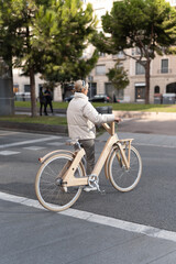 Female cyclist crossing road near park