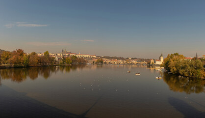Fototapeta premium View of the Charles Bridge and the Vltava River on a sunny day in the city of Prague with a boat on the surface
