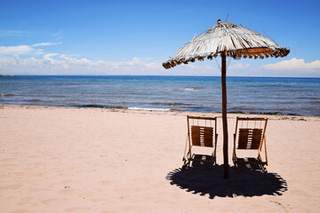 Beach umbrella and chairs with lake Titicaca in the background. No people at the empty beach on Taquile Island in Peru, South America.