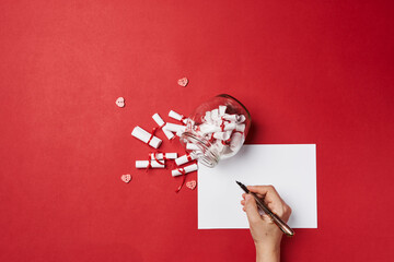 Woman write secret letter. Female hand write secret desires or wishes on piece of paper. A jar of...