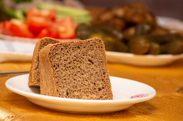 several slices of bread on a white plate against the background of a table with food
