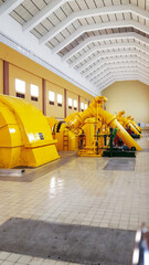 Yellow turbines in machine hall inside power station. Hydro power, electricity and future thinking concept.