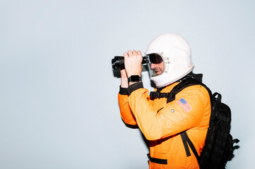 Man with astronaut helmet using binoculars
