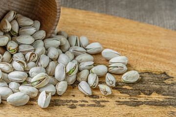 food background of pistachios in a wooden bowl scattered on a wooden board