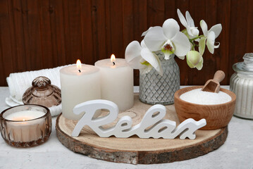 Spa-Arrangement mit Kerzen Handtuch und dem Schriftzug Relax.