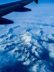 The airplane day sky, view above snow mountains from cabin window. High quality photo