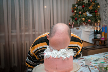The bald guy smears his face on the cake. The man fell face down on the cake.