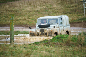 a vintage Land Rover series 2 vehicle driving off-road through deep muddy water Salisbury Plain UK
