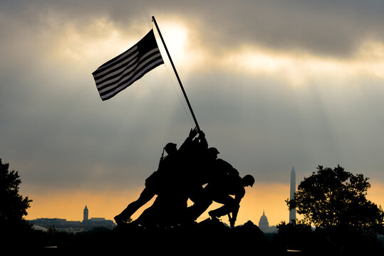 silhouettes of memorials on sunrise in Washington DC. The Memorial honors the Marines who have died defending the US since 1775 and is a prominent tourist attraction in Washington DC. 
