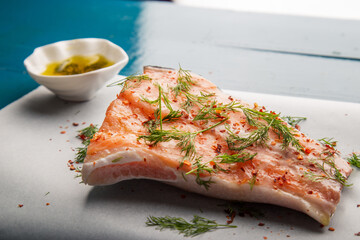 Closeup detail view of salmon steak over blue wooden rustic table ready to grill. Includes copy space.