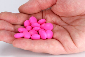 hand of man full of pink pills