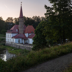 Prioratsky aka Priory palace in Gatchina stands on the shore of the pond. It is surrounded by a green forest. Small mansion, resembling a medieval 18th century European monastery with red tall spires.