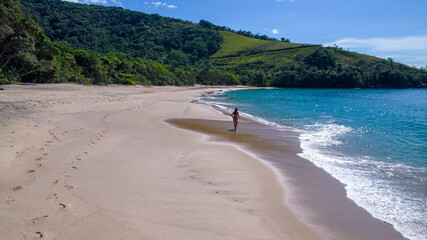 Brazilian woman in bikini on a deserted beach in Ubatuba, São Paulo, Brazil. Playing in the sea...
