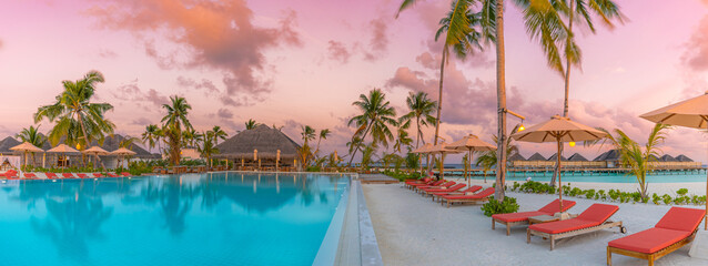 Luxury infinity pool sunset sky in a summer beachfront poolside chairs hotel resort at tropical...