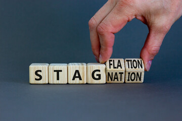 Stagflation or stagnation symbol. Businessman turns cubes, changes the word stagnation to...