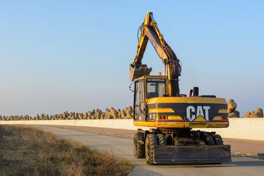 Wladyslawowo, Poland - January 27, 2017: CAT excavator coming back from construction on the quay in the port of Wladyslawowo