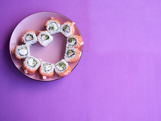 Obraz na płótnie Canvas Sushi set in the shape of a heart on very peri background. Valentine day or March 8th food concept.The concept of a romantic dinner at a sushi bar for February 14th.