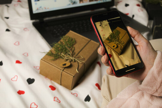 Gift for the new year. The girl takes a picture of a gift on the phone. The girl opens New Year's gifts.