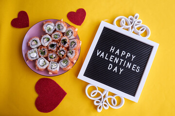 Sushi set in the shape of a heart on yellow background. Valentine day or March 8th food concept.The concept of a romantic dinner at a sushi bar for February 14th.