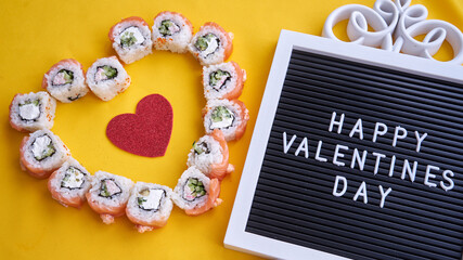 Sushi set in the shape of a heart on yellow background. Valentine day or March 8th food concept.The concept of a romantic dinner at a sushi bar for February 14th.