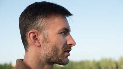 Fototapeta premium Portrait of a handsome man in profile in the park.
