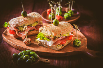Ciabatta sandwich with guacamole, prosciutto, lettuce, tomato and olives