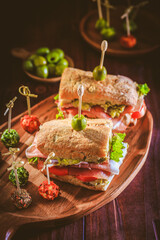 Ciabatta sandwich with guacamole, prosciutto, lettuce, tomato and olives