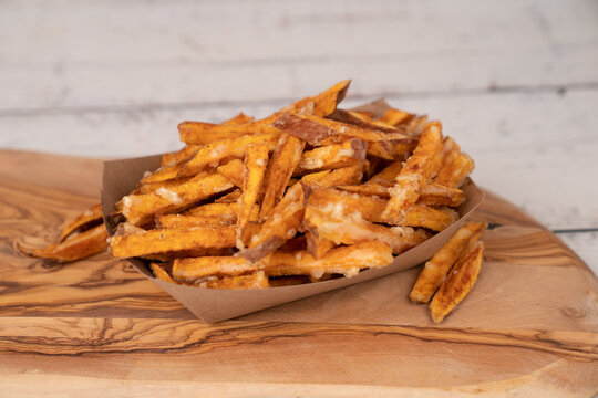 Sweet potato fries on paper container in wood board