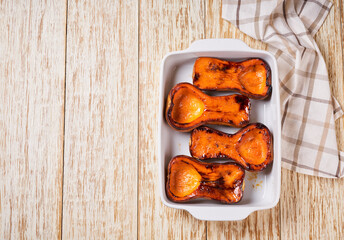 Baked roasted grilled butternut squash on a white wooden table, copy space for text.