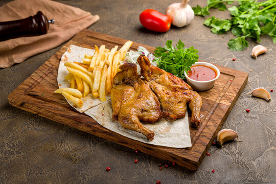 fried chicken tobacco on the board with french fries, red onion and tomato sauce