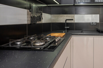 The interior of a modern kitchen in the apartment, cabinets, oven, gas stove, table for cooking.