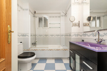 apartment toilet with dark cabinet under the mirror and bathtub with screen