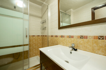 Dark cream toilet with white sink and shower with screen in the background