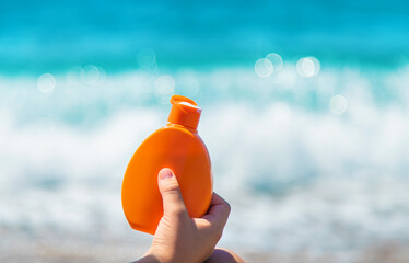 Sunscreen in hands on the beach. Selective focus.