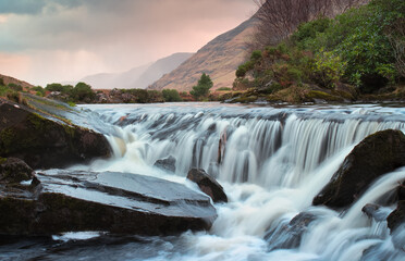 Beautiful sunrise nature scenery of small waterfall on river Erriff with mountains in the background at Aesleagh in county Mayo, Ireland 