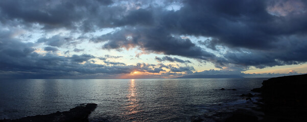 Evening view from tenerife over the atlantic sea to the island of la gomera in the canary islands with heavy clouds and sunset making a scenic dramatic sky