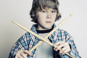 Serious male teenage drummer holding crossed drum sticks