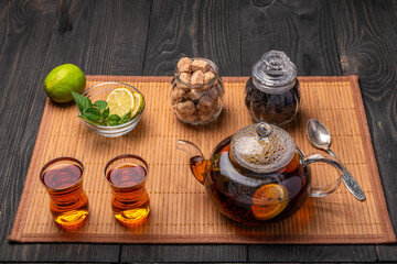 teapot and tea glasses with black tea and lime