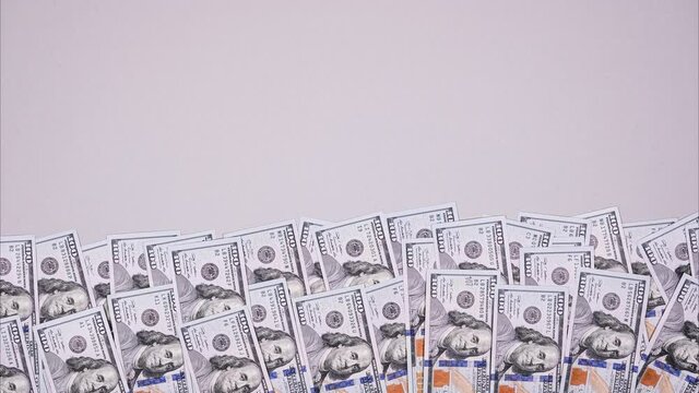 100 dollar bills wiggle on gray background. Stop motion video banner about money with copy space.