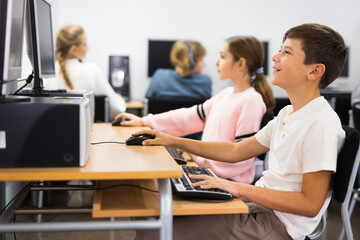 Fototapeta premium Active schoolchildren, preparing lessons in the classroom view the necessary information on the computer to write an abstract