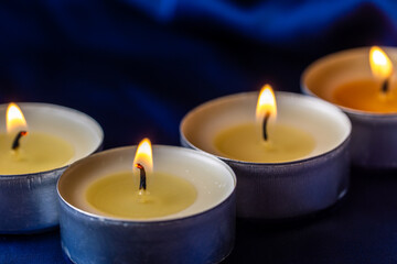 Fototapeta na wymiar Round candles are burning on a blue background. Tea light set. The symbol of romance.
