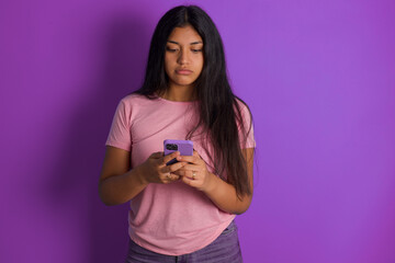 Excited Hispanic brunette girl wearing pink t-shirt over purple background winking and eye hold...