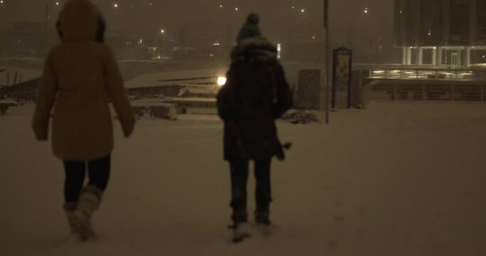 4K Stock footage of people walking in the park during a snowfall blizzard in Vancouver's cityscape at night