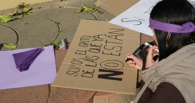 woman making a poster on the ground for feminist protest outdoors