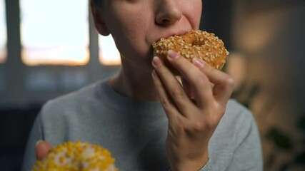 Sweet addiction concept. Woman is eating a donut and is about to eat another one.