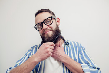 Professional beard care. Handsome bearded man with hairbrush combing his beard. Close-up