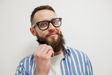 Fototapeta premium Professional beard care. Handsome bearded man with hairbrush combing his beard. Close-up
