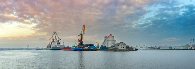 seaport with cranes and ships under a beautiful sunset sky, panorama