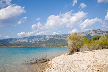 The banks of the Lac de Sainte-Croix with its white pebble beach in Europe, France, Provence Alpes Cote dAzur, in the Var, in summer, on a sunny day.